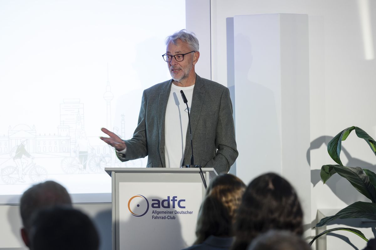 Der ADFC-Bundesvorsitzende Frank Masurat steht hinter einem Rednerpult und spricht zum Publikum. 